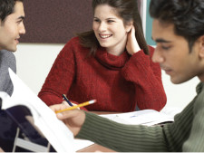 Person looks at homework assignment with smiling student in background