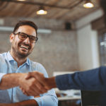 Man laughs while shaking another person's hand