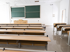 Empty classroom features chalkboard and empty desks