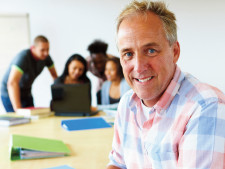 Person smiles at camera while students collaborate in background