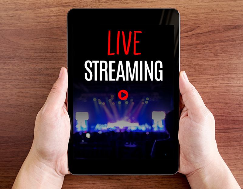 Person holds tablet with the words "live streaming" on screen and play button