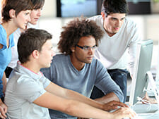 Group of students look at computer and collaborate online group projects