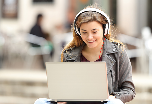 Person smiles at computer with headphones