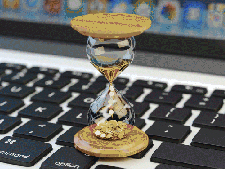 Computer keyboard has sand hourglass sitting on top of it