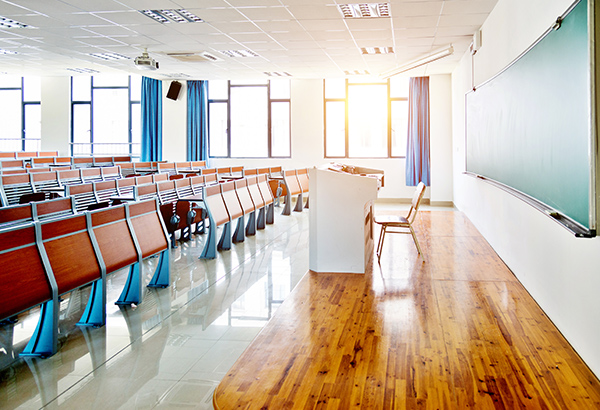 Large, empty lecture hall features bright, windows with projector screen