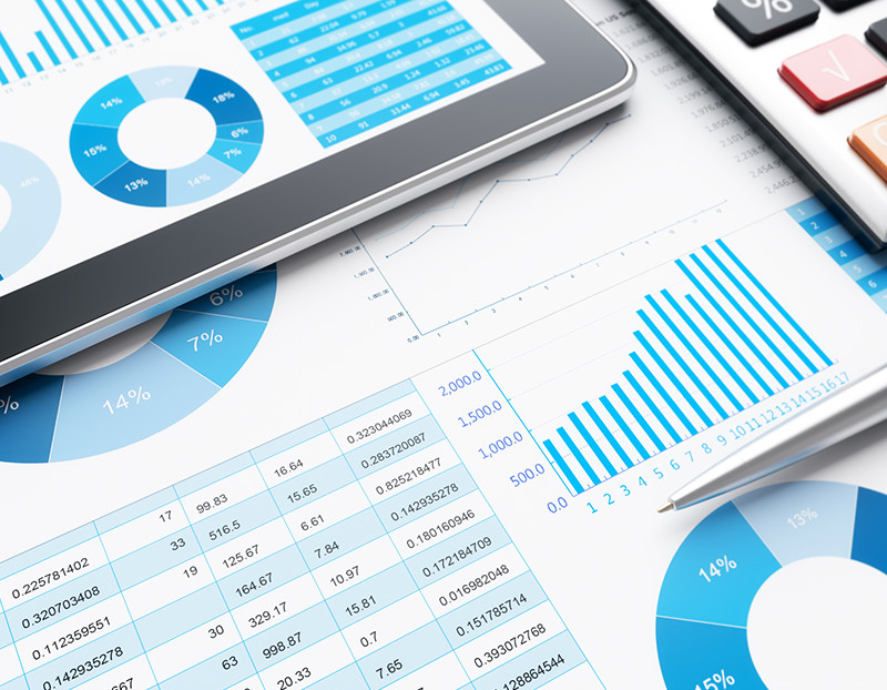 Data, charts, and numbers appear on tablet and papers next to calculator