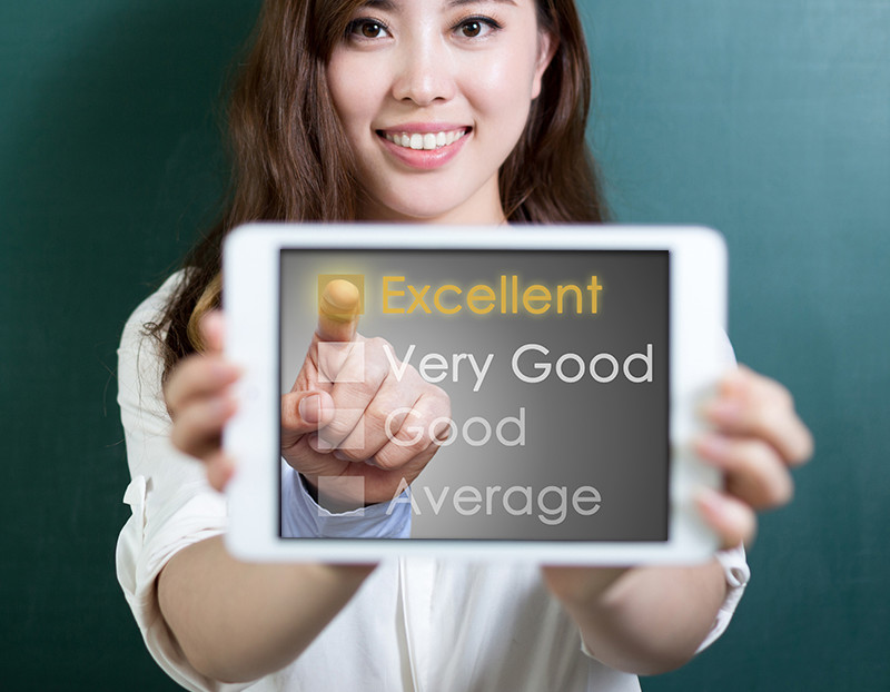 Female holds up device with options displaying "Excellent, Very good, Good, and Average," while finger points to "Excellent"