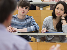 Two students listen to teacher with hand on head looking bored