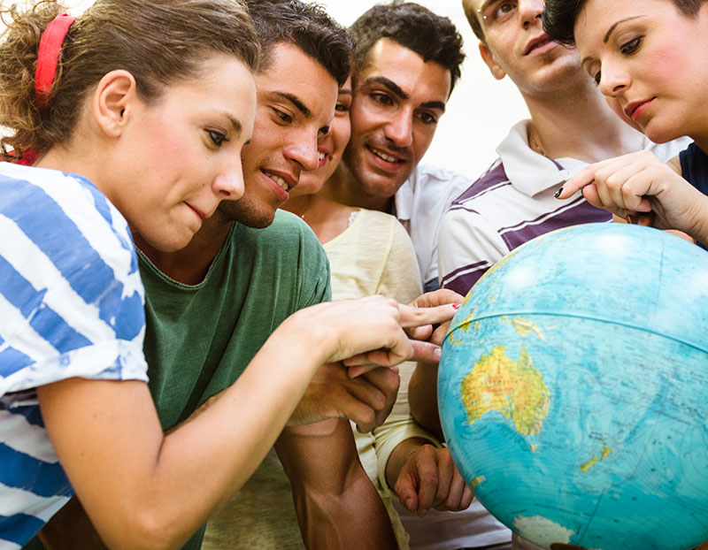 Students point to different places on a globe for Intercultural Awareness