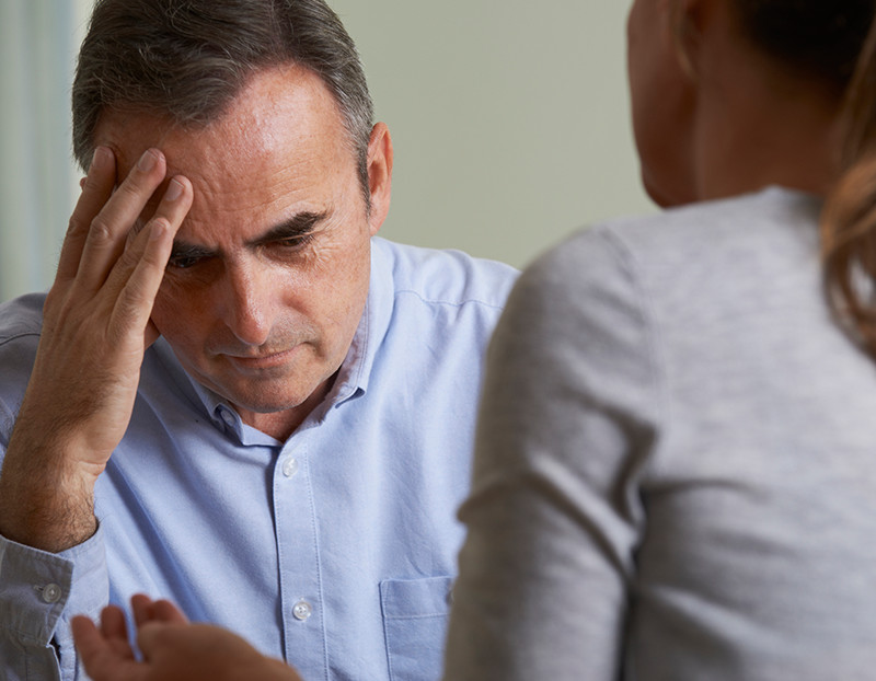Faculty member places head in hands in distress as he talks to another faculty member