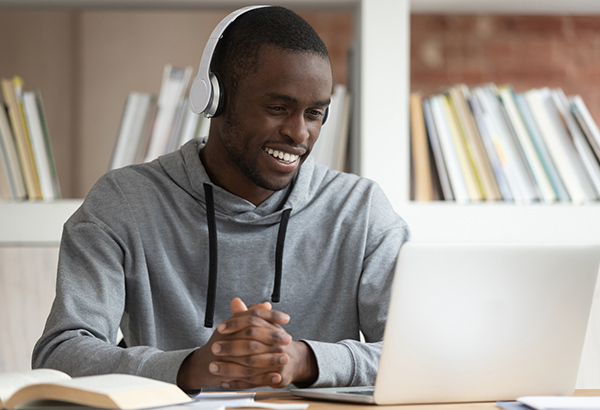 Student with headphones smiles for a meaningful online learning experience