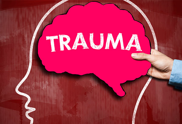 Teacher holds "trauma" sign for neuroscience of trauma