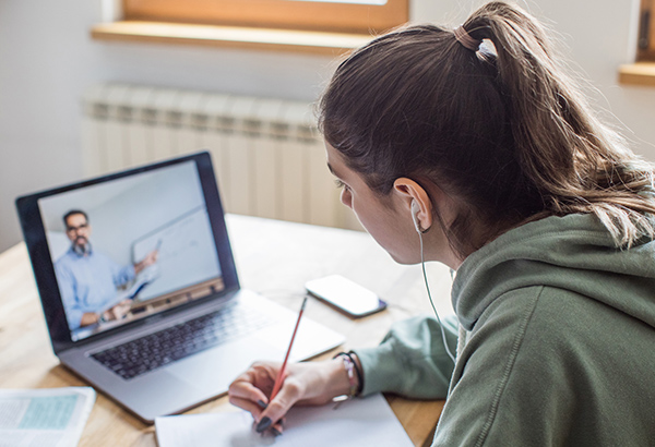 female-student-with-headphones-taking-notes-in-online-class