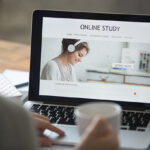 Person with coffee on computer for online pedagogy