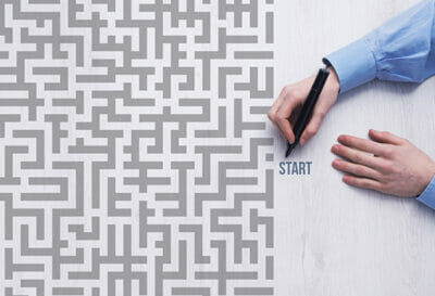 person-with-pen-working-through-gray-maze