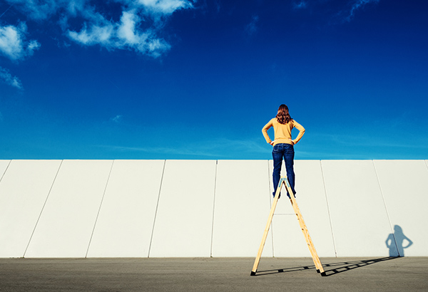 woman-on-ladder-standing-above-obstacles-wall-proudly