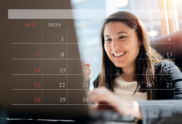 woman-smiling-working-on-computer-with-calendar