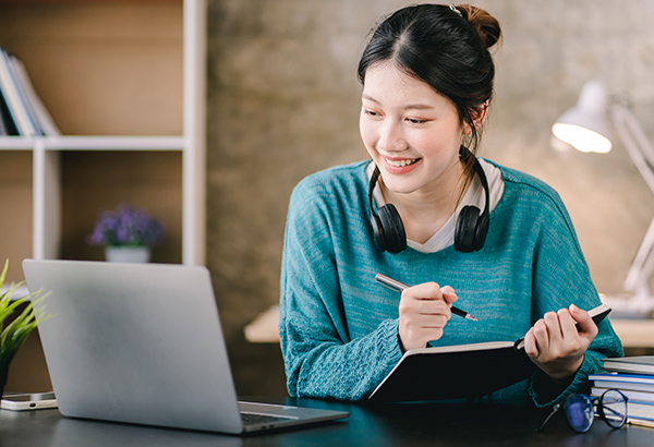 Woman-at-laptop-smiling-taking-notes