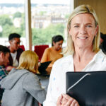 woman-standing-proudly-in-classroom-as-her-students-work