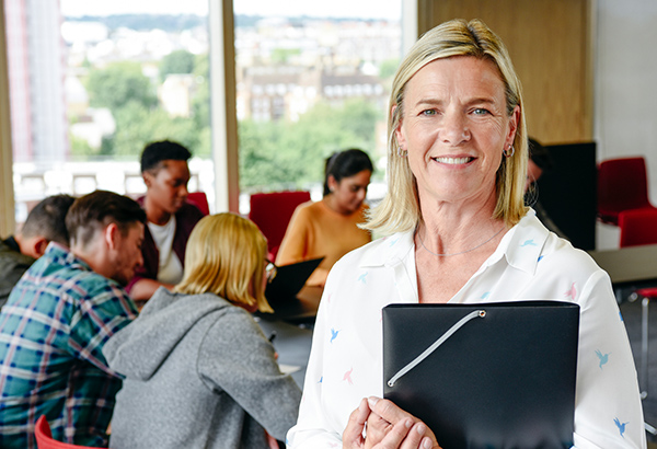 woman-standing-proudly-in-classroom-as-her-students-work