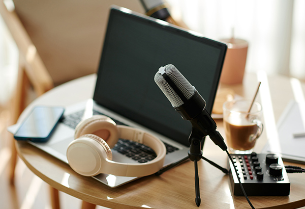 desk-with-laptop-microphone-headphones-and-podcast-equipment