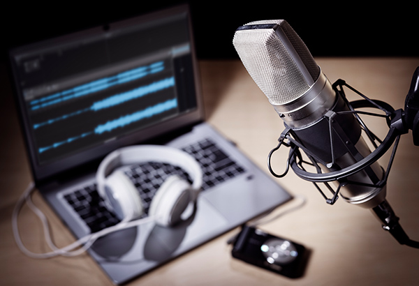 podcast-equipment-set-up-on-desk-with-computer-headphones-and-microphone
