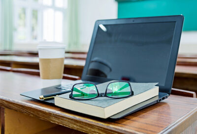 glasses-on-top-of-book-on-top-of-laptop-in-classroom