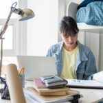 young-person-in-room-at-desk-studying-with-open-books