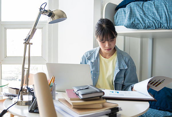 young-person-in-room-at-desk-studying-with-open-books