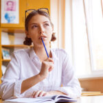 student-with-glasses-at-desk-working-on-homework-thinking